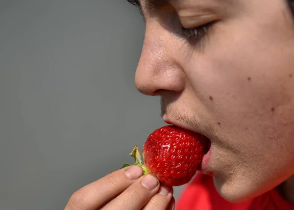 Niño caucásico que está comiendo una fresa —  Fotos de Stock