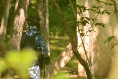 Paintball savaşı. Oyuncular bir pusuda ormanda yararlanmak