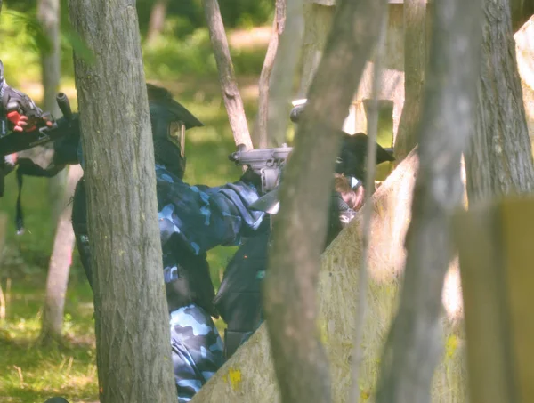 Batalla de paintball. Los jugadores aprovechan el bosque para acechar a un — Foto de Stock