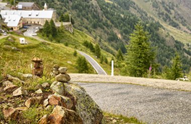 Taşlar bir dağ yolu boyunca zen anıt olarak yığılmış, arka planda bir ilçe bulanık ve ayırt edilemez.