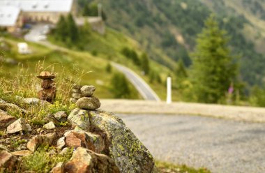 Taşlar bir dağ yolu boyunca zen anıt olarak yığılmış, arka planda bir ilçe bulanık ve ayırt edilemez.