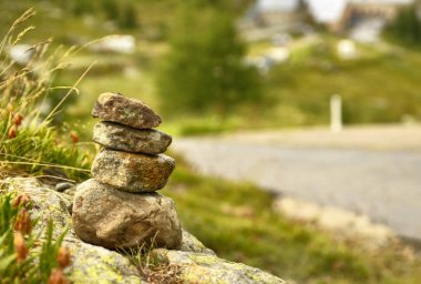 Taşlar bir dağ yolu boyunca zen anıt olarak yığılmış, arka planda bir ilçe bulanık ve ayırt edilemez.