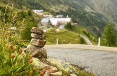 Taşlar bir dağ yolu boyunca zen anıt olarak yığılmış, arka planda bir ilçe bulanık ve ayırt edilemez.