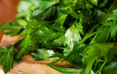 Tahta bir kesme tahtasının üzerinde duran maydanozu yakından çek. Yaprakların üzerinde küçük su damlaları