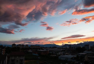 Torino, Piedmont, İtalya. Mayıs 2020. Şehrin kuzey banliyölerinde sıcak ve parlak renkli bulutlarla nefes kesici bir günbatımı var. Alpler 'in dağları ufuktadır. Stadyumun sütunları