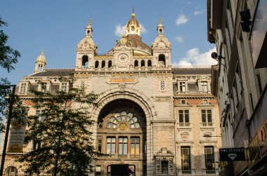 Antwerp, Flanders, Belçika. Ağustos 2019. Zorlu tren istasyonunun ön cephesi. Öğleden sonra güneşi onu sıcak ışığıyla aydınlatır. Beyaz bulutlu mavi gökyüzü.