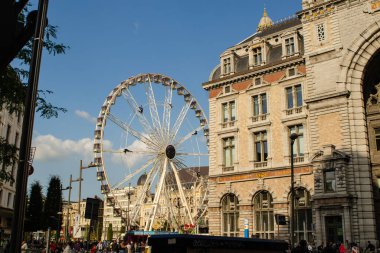 Antwerp, Flanders, Belçika. Ağustos 2019. Zorlu tren istasyonunun ön cephesi. Solda dönme dolap var. Beyaz bulutlu mavi gökyüzü.