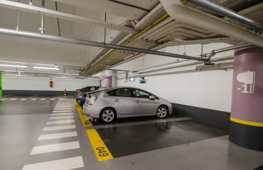 Antwerp, Belçika. Ağustos 2019. Şehirdeki yeraltı otoparklarından biri. Neon ışıkları ve tabelalar numaralandırılmış park yerleri ve yaya yolları için güvenlik garantisi..