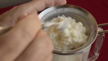 Kefir granüllerini yakından çek, çocuğun elleri nazikçe onları tutuyor. Eller taneciklerin kasenin içine kaymasına izin verdi.. 