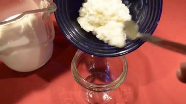 Kefir 'in dökülmesi sırasında yanal görüş. Granüller muhafaza edilirken elek ağından gelen mayalanmış süt açıkça görülebilir.