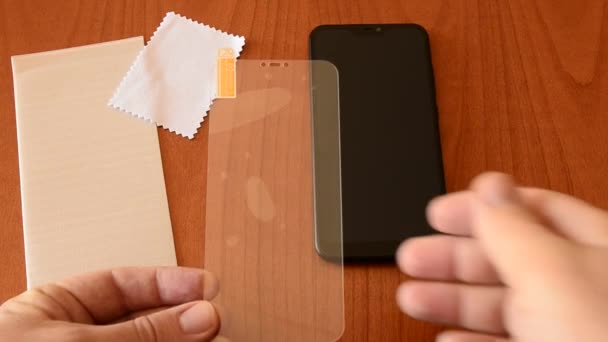 Pour installer la vitre de protection sur le smartphone, le film doit être retiré. Les mains soutiennent la glissière et soulèvent le film à l'aide de l'onglet approprié.