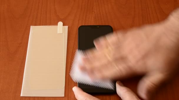 Avec un bâton de microfibre, le résidu de détergent est séché de l'écran, une main soulève le téléphone tandis que l'autre frotte l'écran dans un mouvement circulaire.