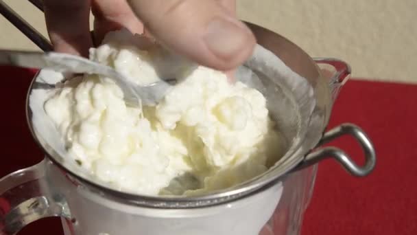 Kefir用勺子把它移到Colander里过滤白色和乳白色的雪貂滴落在雪貂的底部 — 图库视频影像