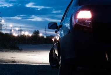 Arka görünümü araba tampon seviyesi. Kırmızı renkli ışıklar. Yaz şehirde gece sürmek