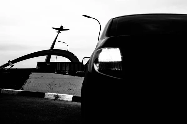 Zwart-wit foto. De auto voor het monument. Achteraanzicht. Reizen in de herfst. — Stockfoto