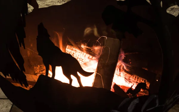 Wood hearth for heating in winter on the street. Wood, fire, metal figures. Black and yellow.Winter outside.