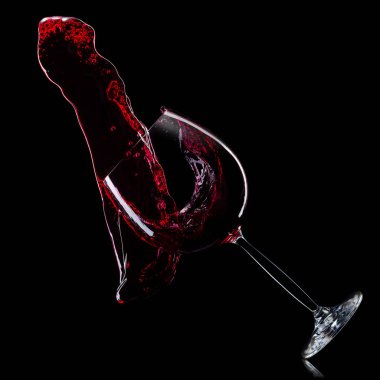 Siyah arka planda izole sıçramaları ile kırmızı şarap için cam.