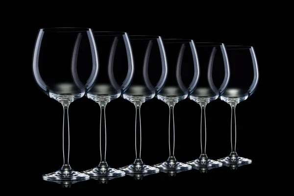 Zestaw pustych okularów do czerwonego wina w rzędzie odizolowanym na czarnym tle. — Zdjęcie stockowe