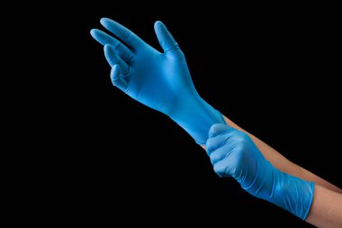 Ellerine tıbbi eldiven takan doktor siyah arka planda, kırpma yolu ile izole edilmiş. Salgın ve virüslere karşı korunma kavramı.