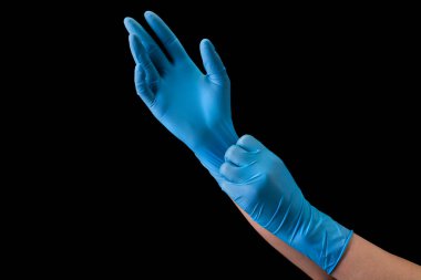 Ellerinde tıbbi eldiven olan doktor siyah eldiven takıyor.