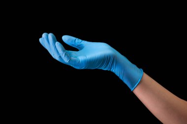 Doktor 'un eli steril tıbbi eldivenlerle siyah arka planda izole edilmiş, kırpma yolu olan bir şey gösteriyor. Salgın ve virüslere karşı korunma kavramı.