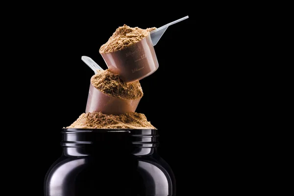 一勺巧克力蛋白质粉末饮料 装在黑色塑料容器中 与黑色背景隔离 有切割路径 健体补助的概念 — 图库照片
