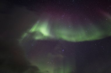 Bulutlu gece gökyüzünün üstündeki kuzey ışıkları 