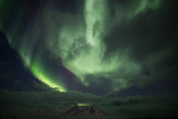 Northern lights above the cloudy night sky 