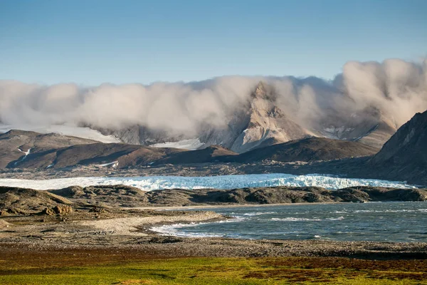 Göz kamaştırıcı kayalık karlı dağların fotoğrafları alçak, güzel, gri bulutlar.