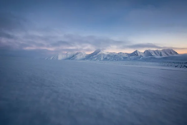 山を背景にパステルピンクや青のトーンで滑らかな雪の表面 — ストック写真