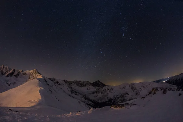 Karlı dağların üzerinde yıldızlı gökyüzü