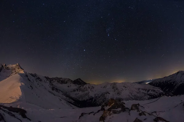 Karlı dağların üzerinde yıldızlı gökyüzü