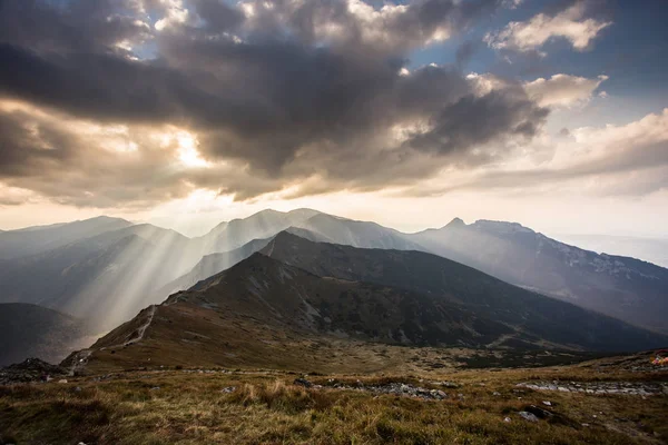 Polonya 'daki Tatra dağlarının üzerindeki bulutların arasından güneş ışığı parlıyor.