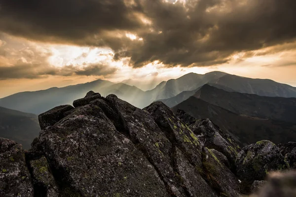 Polonya 'daki Tatra dağlarının üzerindeki bulutların arasından güneş ışığı parlıyor.