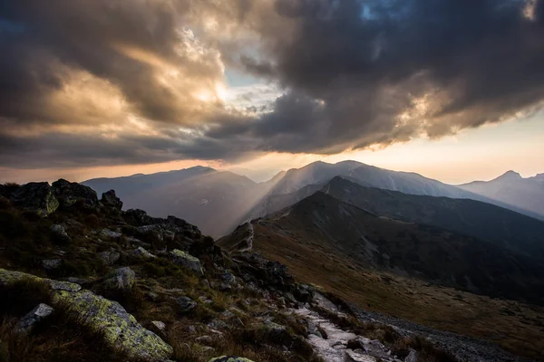 Polonya 'daki Tatra dağlarının üzerindeki bulutların arasından güneş ışığı parlıyor.
