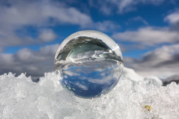 在冰冷的雪地上 一个玻璃球的照片 倒影中的风景 — 图库照片