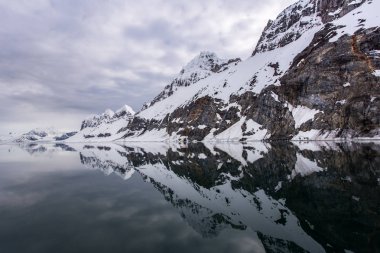 Sudaki yansımalarıyla karlı tepeler