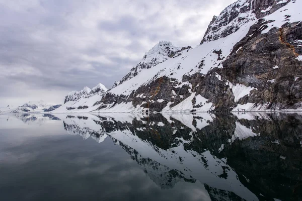 Sudaki yansımalarıyla karlı tepeler
