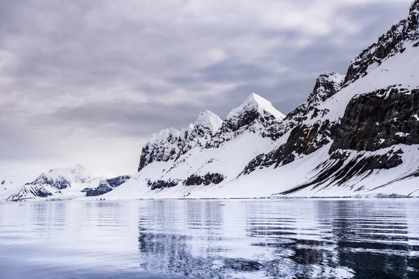 水から北極の雪の岩の多い山の海岸での眺め — ストック写真
