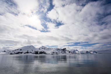 Kuzey Kutbu 'ndaki karlı kayalara ve sudaki buzullara bakın.
