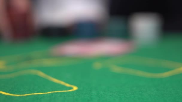 Τζογαδόρος κάνει στοίχημα, πιέζοντας κόκκινο πόκερ μάρκες προς πράσινο καζίνο στο τραπέζι — Αρχείο Βίντεο