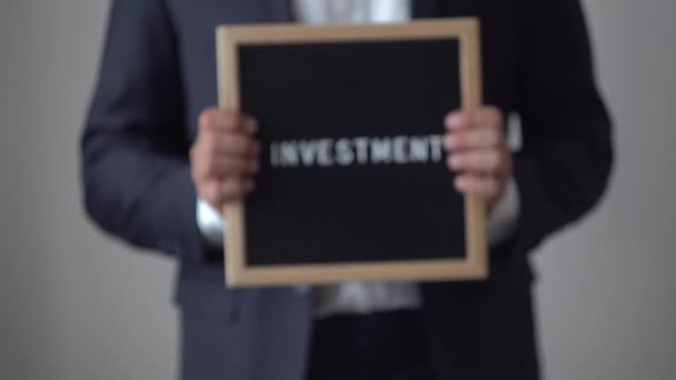 Word investeringen van Letters op tekst bord in handen van de anonieme zakenman — Stockvideo