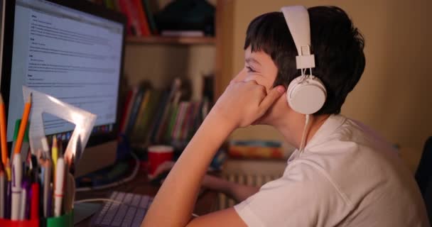 Een jongen die thuis een computer gebruikt. tiener zoekt naar informatie op het internet. huiswerk op de computer online. online training tijdens de coronavirusepidemie. — Stockvideo