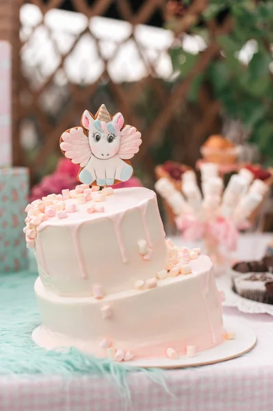 sweet birthday cake with unicorn decoration on table