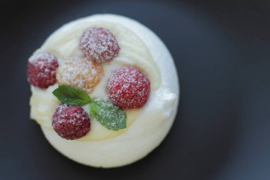 siyah plaka üzerinde sarı ve kırmızı ahududu ile beyaz beze kek, metin için yer 