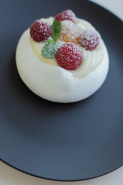 siyah plaka üzerinde sarı ve kırmızı ahududu ile beyaz beze kek, metin için yer 