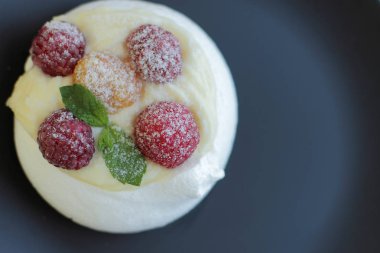 siyah plaka üzerinde sarı ve kırmızı ahududu ile beyaz beze kek, metin için yer 