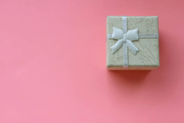 small present box with ribbon on pink background