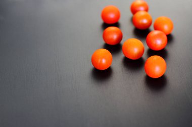 Kırsal siyah zemin üzerinde küçük kırmızı kiraz domatesleri, üst görünüm, kopyalama alanı