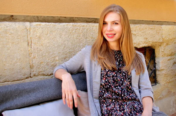 Girl smiling with braces, dental care and cheerful, long blond hair woman sitting in cafe and smile showing her teeth